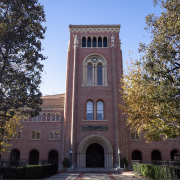 Bovard Auditorium partially covered by trees and illuminated by the sunlight